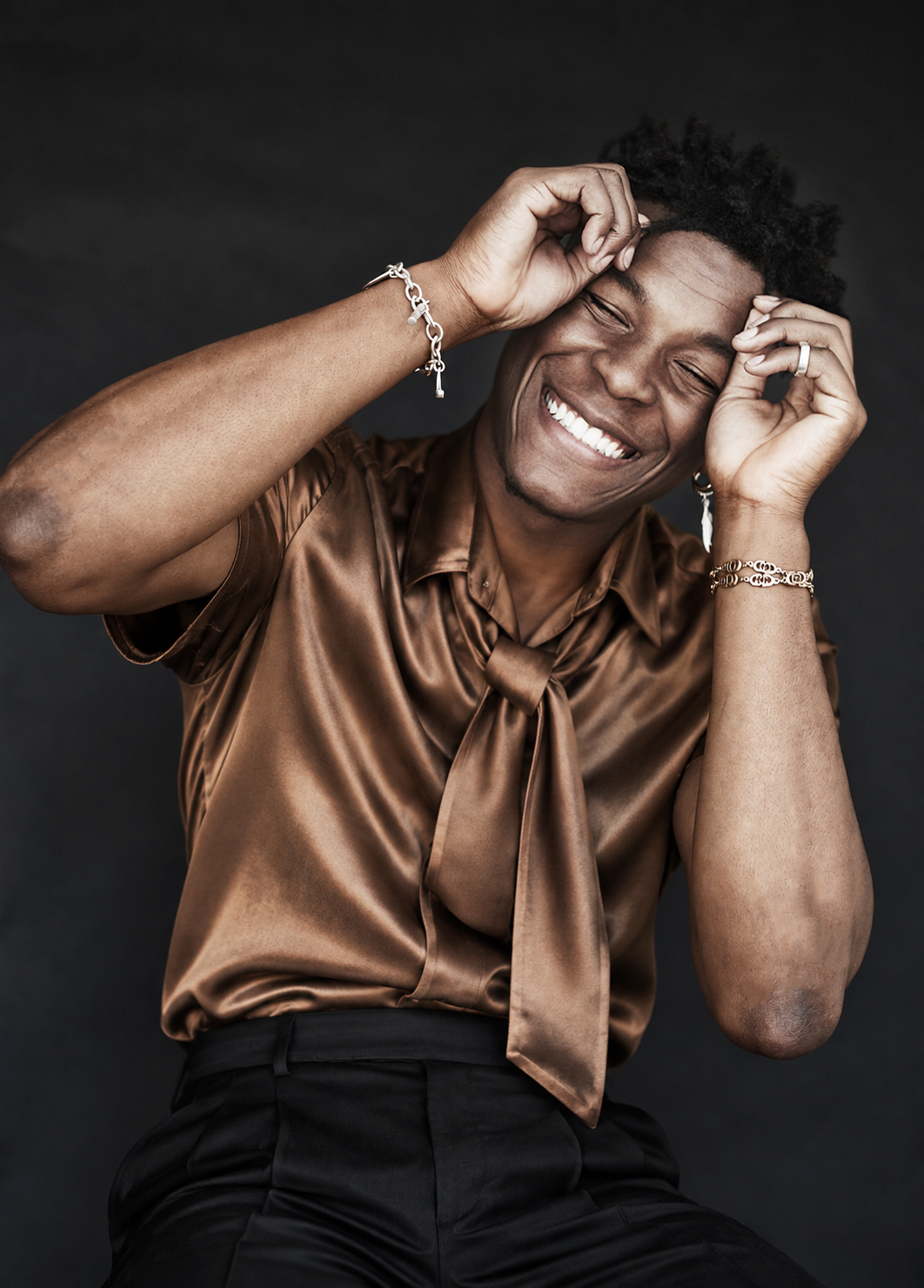 Laughing portrait in a bronze shirt against a dark backdrop