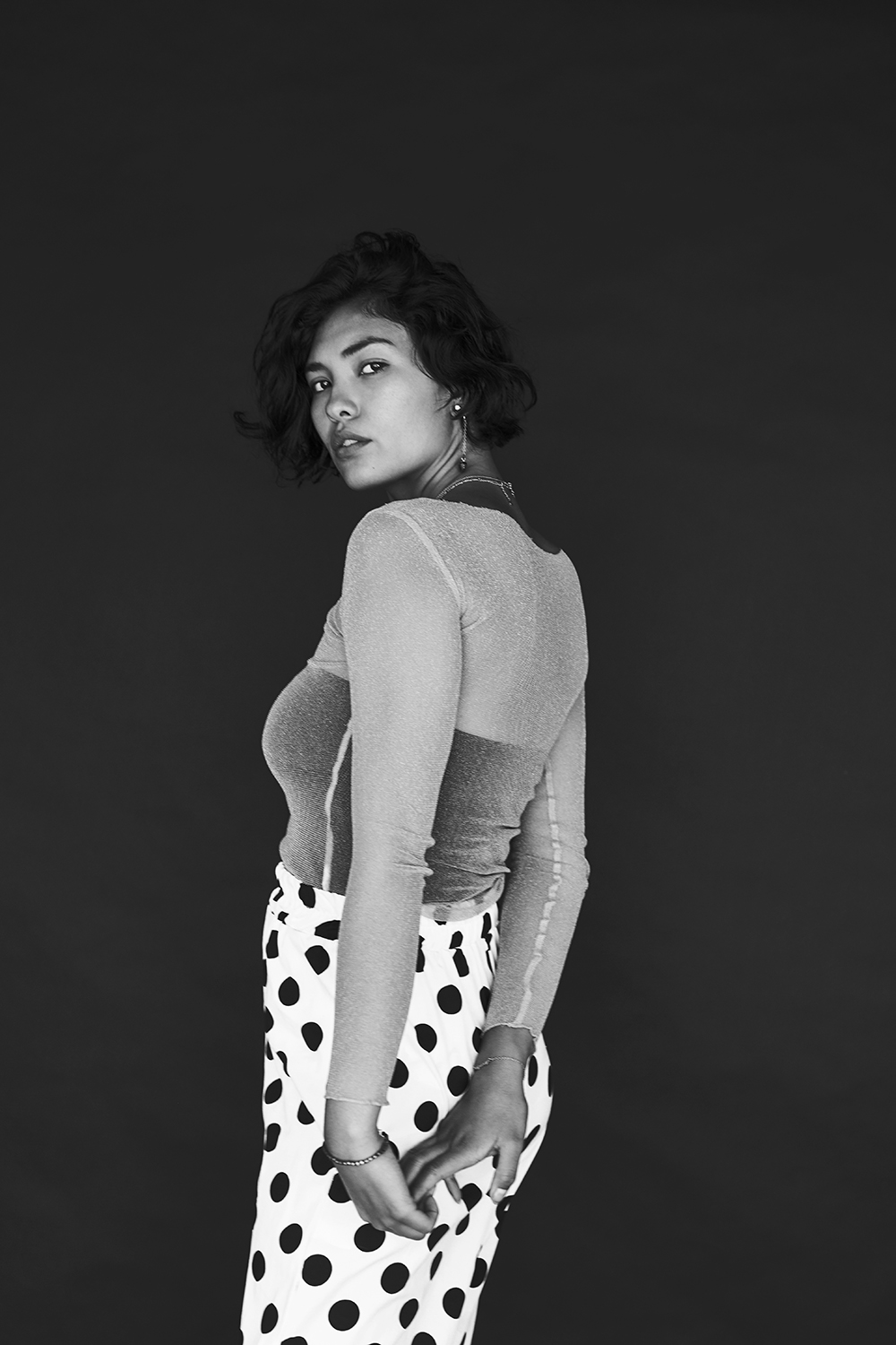 Black and white standing portrait with a patterned skirt