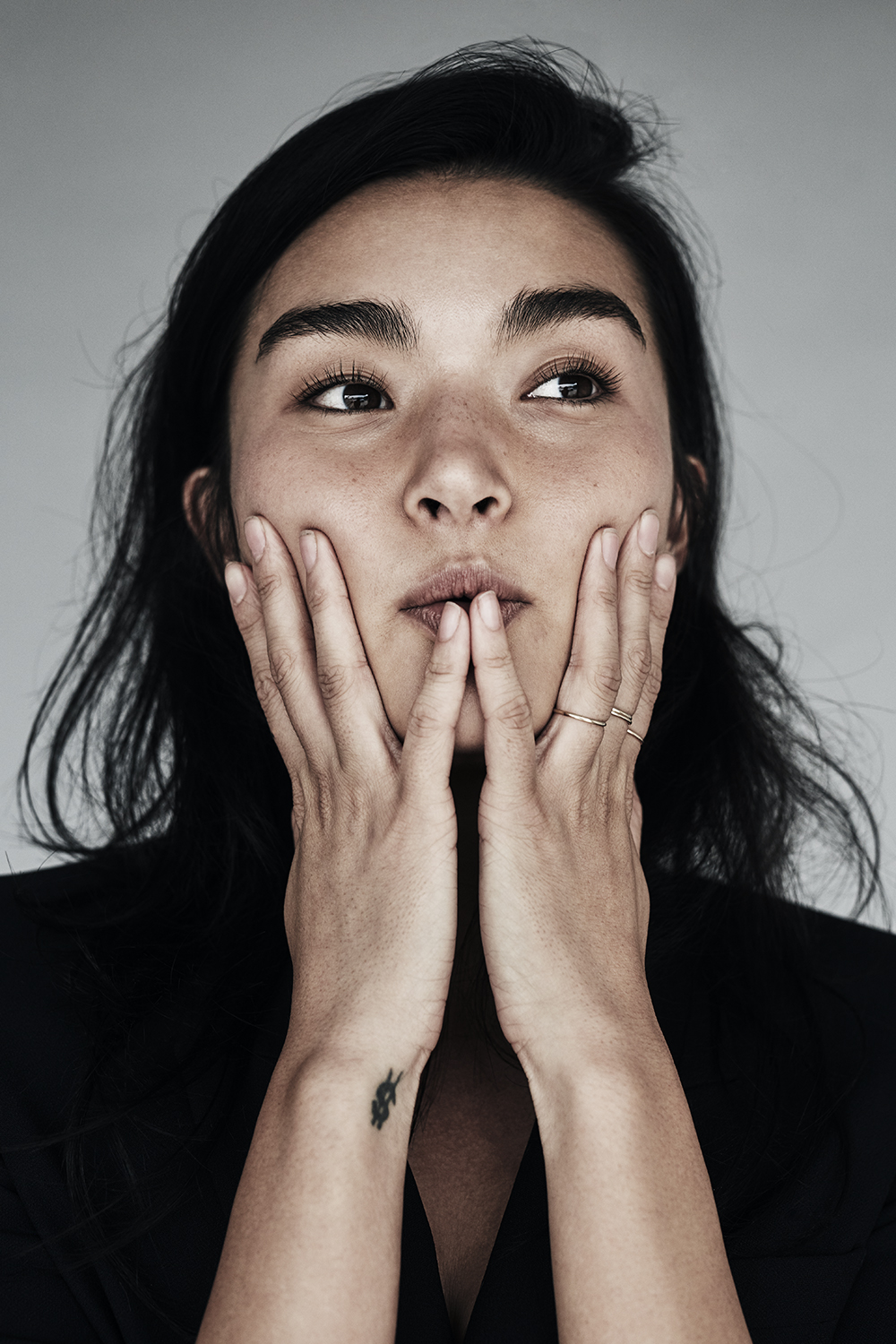 Portrait with hands against cheeks, looking to the side