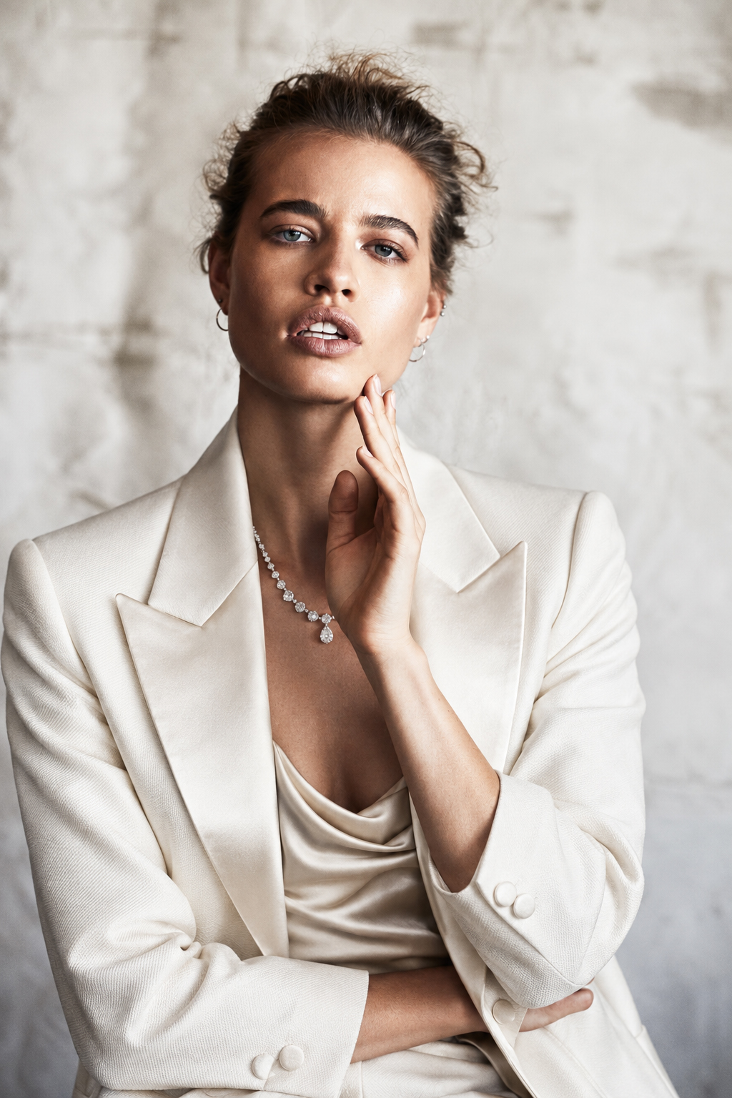 Studio portrait in a white suit with a hand at the neck