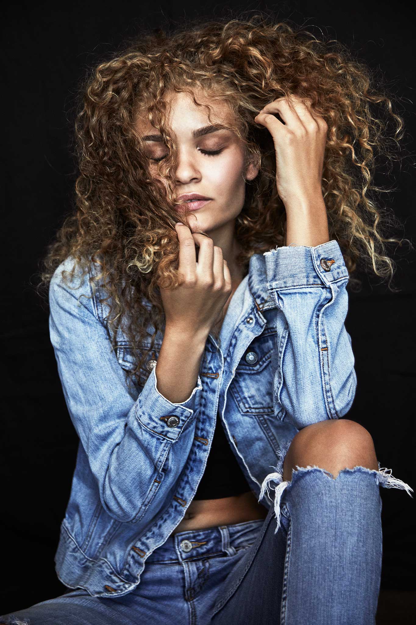 Seated portrait with curly hair and a denim jacket