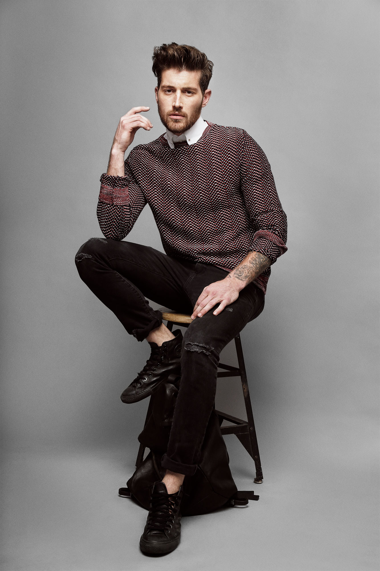 Full-length seated portrait in a patterned sweater